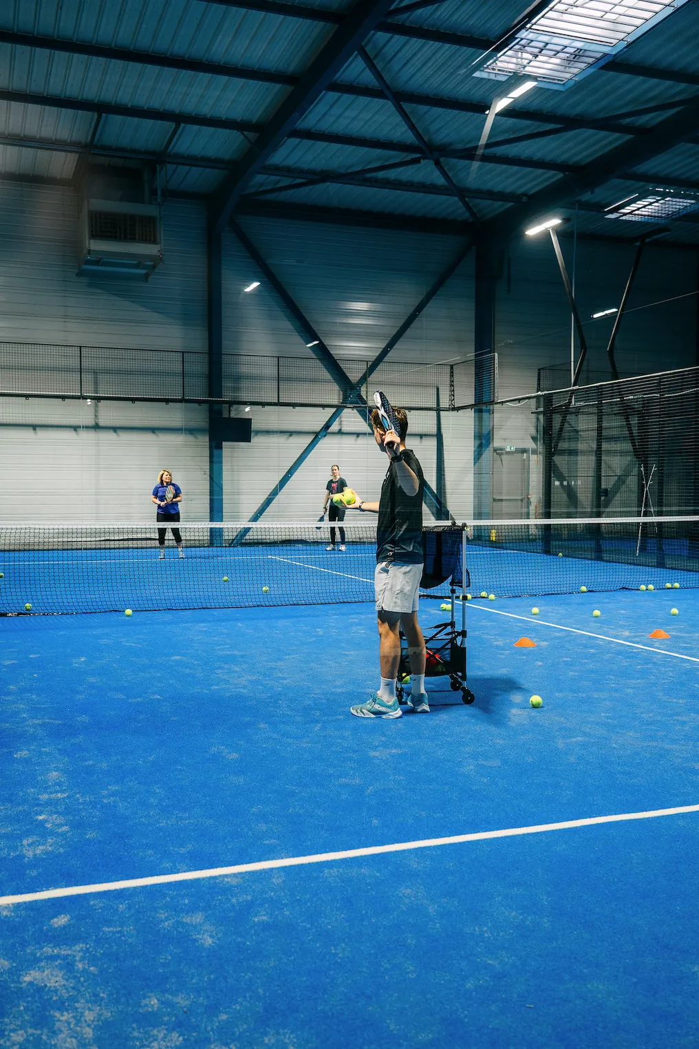 Coach au panier de balles pendant un cours collectif